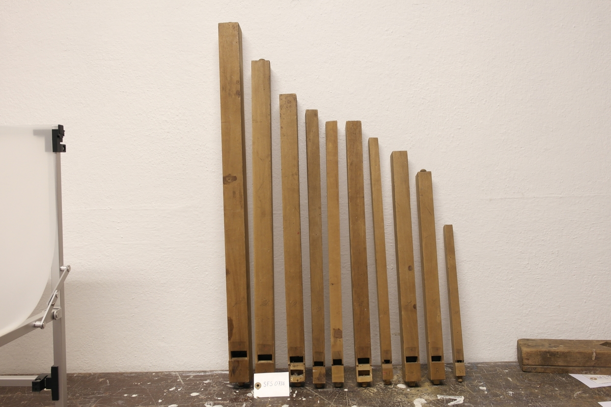 Ti orgelpiper (a-j) i bjørk (?). Pipene er formet som firkantede prismer i ulike størrelser. Ulik størrelse gir ulike toner. Det er sannsynligvis tonene som er notert på hver enkelt pipe.