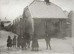 Barn foran trehus i snødekt gate