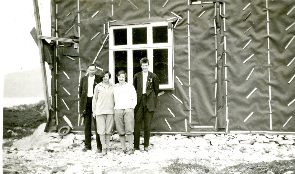 2 menn og 2 kvinner fotografert foran eit hus under bygging