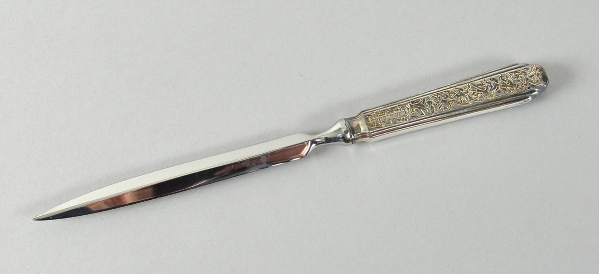 Brevkniv av sølv med krystallmønster og logo for Lillehammer '94 inngravd på skaftet. På baksiden er det inngravert piktogrammer.