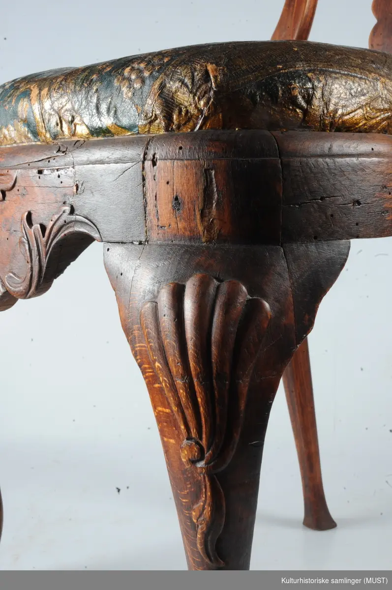 Stolen er av den almindelige rokokkotypen. Ryggen er åpen med et profilert brett som ender i en musling. Sargen har også et usymmetrisk rokokko-ornament. Stolen er trukket med gyldenlær, blå bunn.