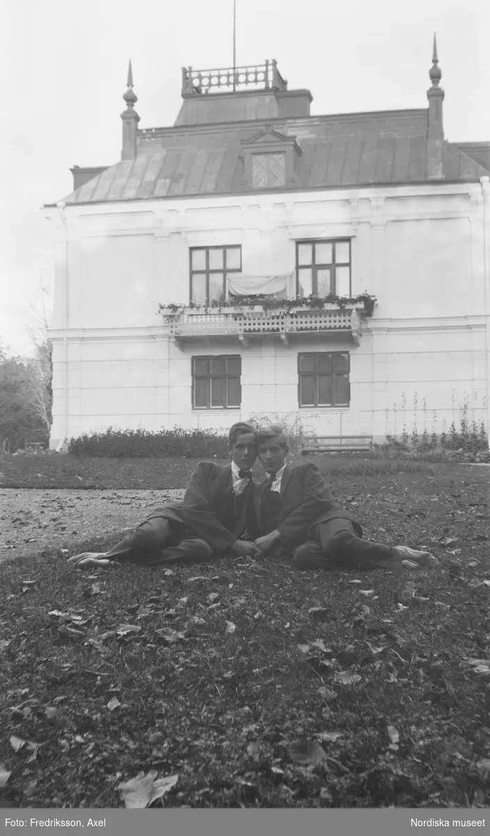 Trädgårdsarbetare på Fogelstad. Porträtt att av två unga män i hefigur , halvliggandes på gräsmattan. De håller varandra i hand.