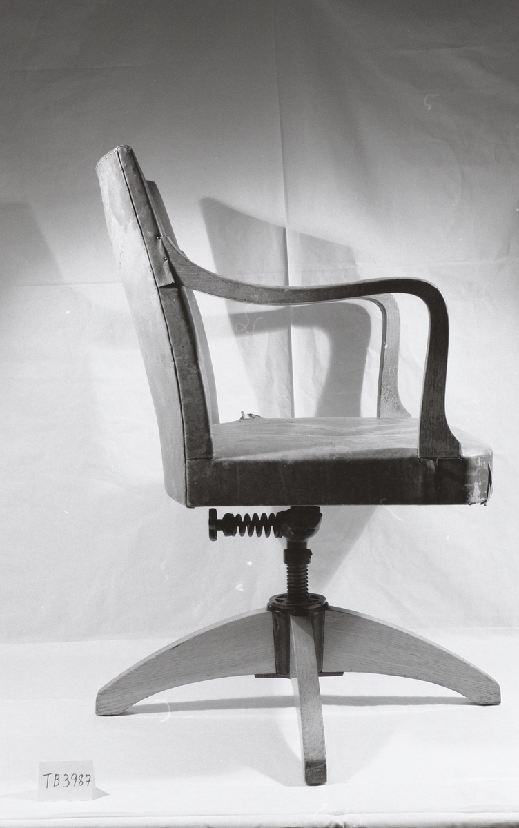 Stolen i  eik fra 1920-tallet har vært lakkert. Den er fjærbelastet og har originaltrekk i lær. Det er hull i trekket og en liten sprekk i siden på stolen.