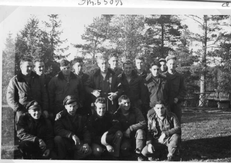Sexton män uppställda på två led, de främre sitter på knä. Alla klädda i flygarjacka/overall. Det är besättningarna på B-17 G #42-102905 samt #43-38426 som nödlandade i Jönköping den 7 oktober 1944 i Jönköping. 
Sittande från vänster: F/O Allen Fischer pilot på #426, 1st Lt Clarence R Jennings pilot på #905, 2nd Lt Robert Wagoner bombfällare #426, troligen T/Sgt Hardy Bell toppskytt #905, Sgt Lester Kern midjeskytt #426.
Stående från vänster: troligen Sgt Joseph Chickola ball turret gunner #426, troligen F/O Thomas Carnegie andrepilot på #426, 2nd Lt Dick Garland andrepilot på #905, F/O Anthony Cannizarro navigatör #426, okänd, okänd, okänd, S/Sgt John Wood akterskytt #905, S/Sgt Charles Spornick ball turret gunner #905, T/Sgt Walter Marr radio operatör #905, Okänd.