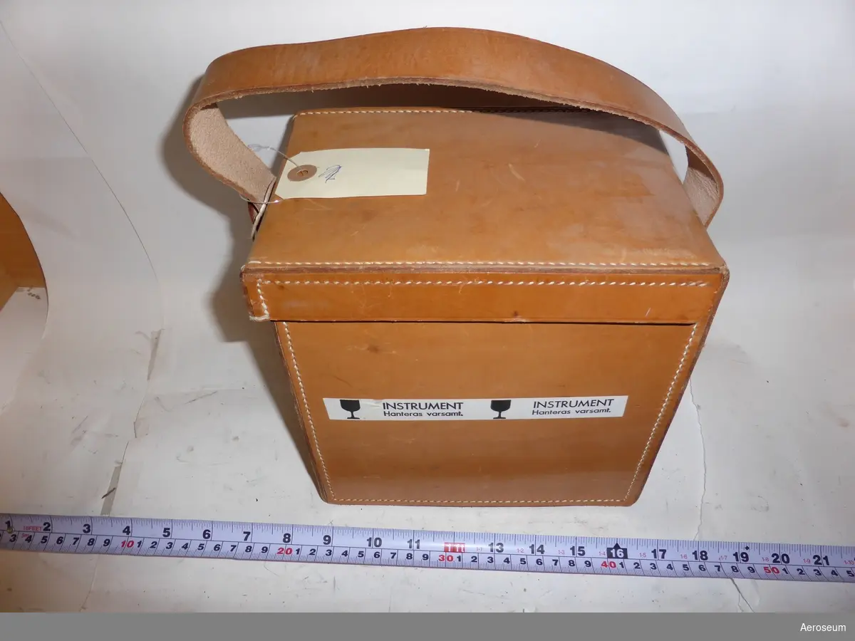 En nätskrivare i brun läderväska. Nätskrivaren har en svart sladd och är tillverkad av Staub & Co. i Schweiz. I läderväskan finns även en papperspåse med 66 stycken diagram/skalskivor. Väskans lock har ett litet lås och en tillhörande nyckel hänger från väskans bärrem.