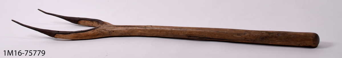 Grep av trä, med två spetsar beslagna med järn, svängd form.