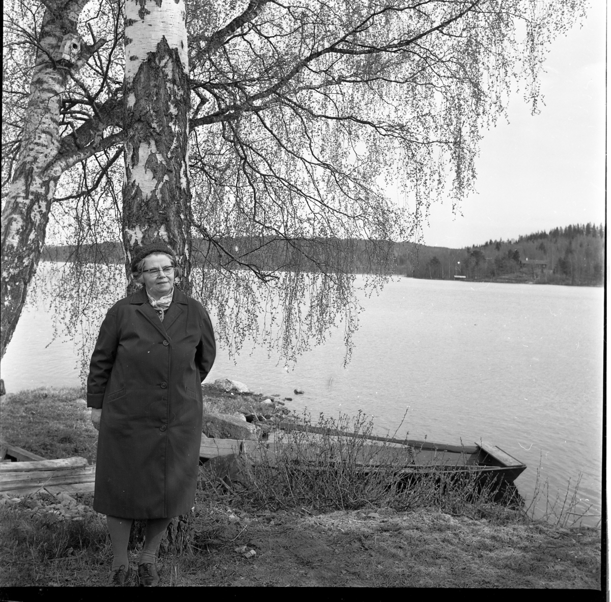 Reseombudet Eva Blomkvist i Bunn står vid en björk, vid sjön Bunn med en eka i bakgrunden.