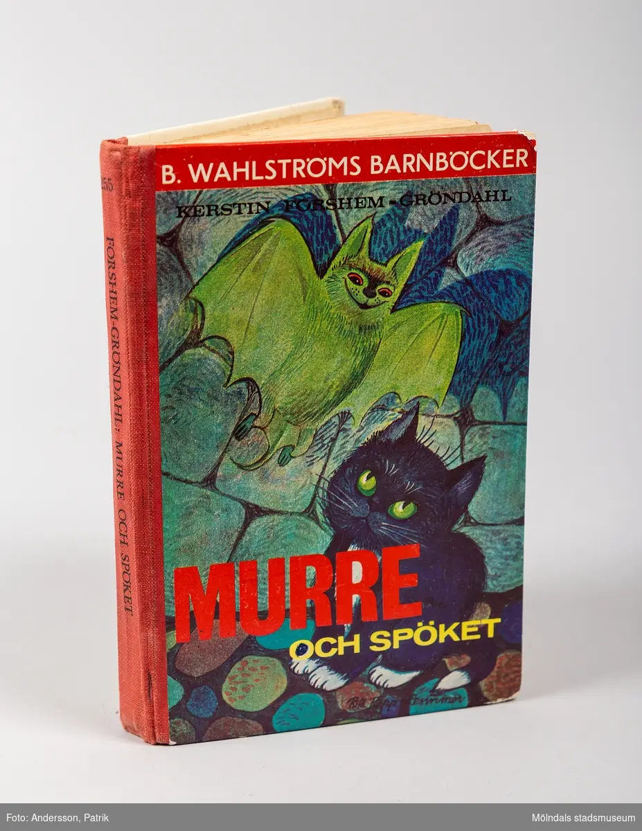 Barnbok: "Murre och spöket" av Kerstin Forshem-Gröndal utgiven av B.Wahlströmsförlag. Storleken på boken är 11x16 centimeter. På det tecknade omslaget finns en svart katt med gröna ögon och en fladdermus. Bokryggen är i röd textil.