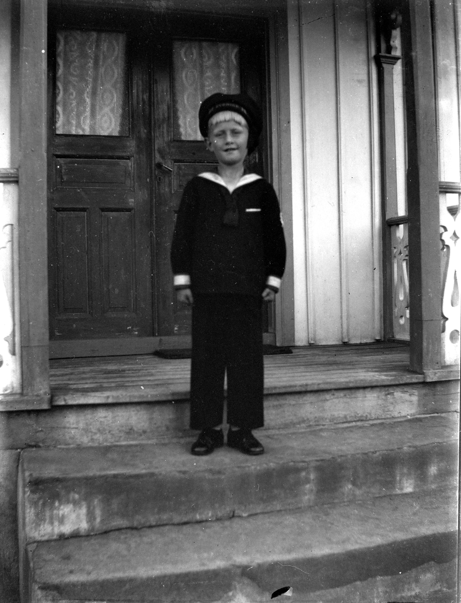 En liten pojke i sjömanskostym med mössa och finskor på Lines veranda.
(Se även bildnr EA1281)