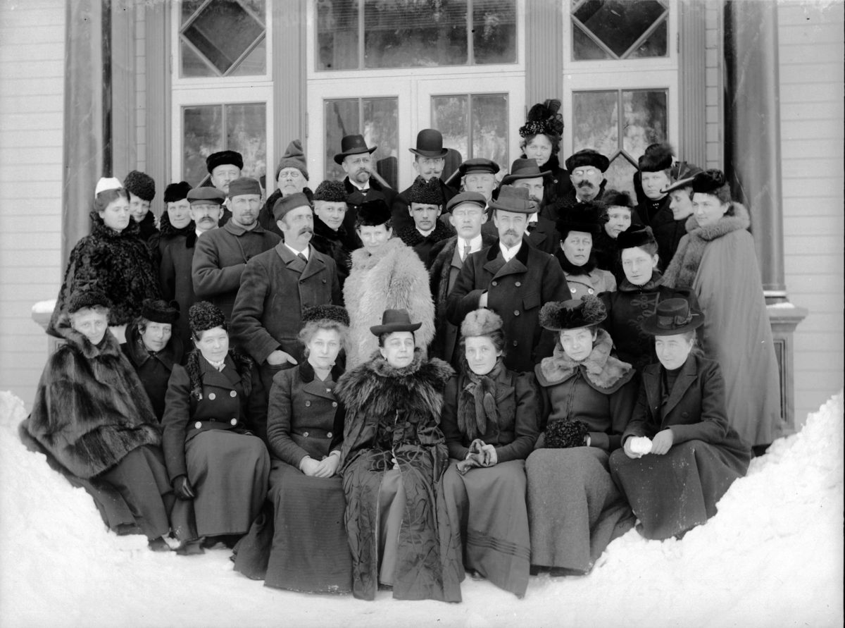 Gruppe med kvinner og menn utenfor et vindu, vinterbilde