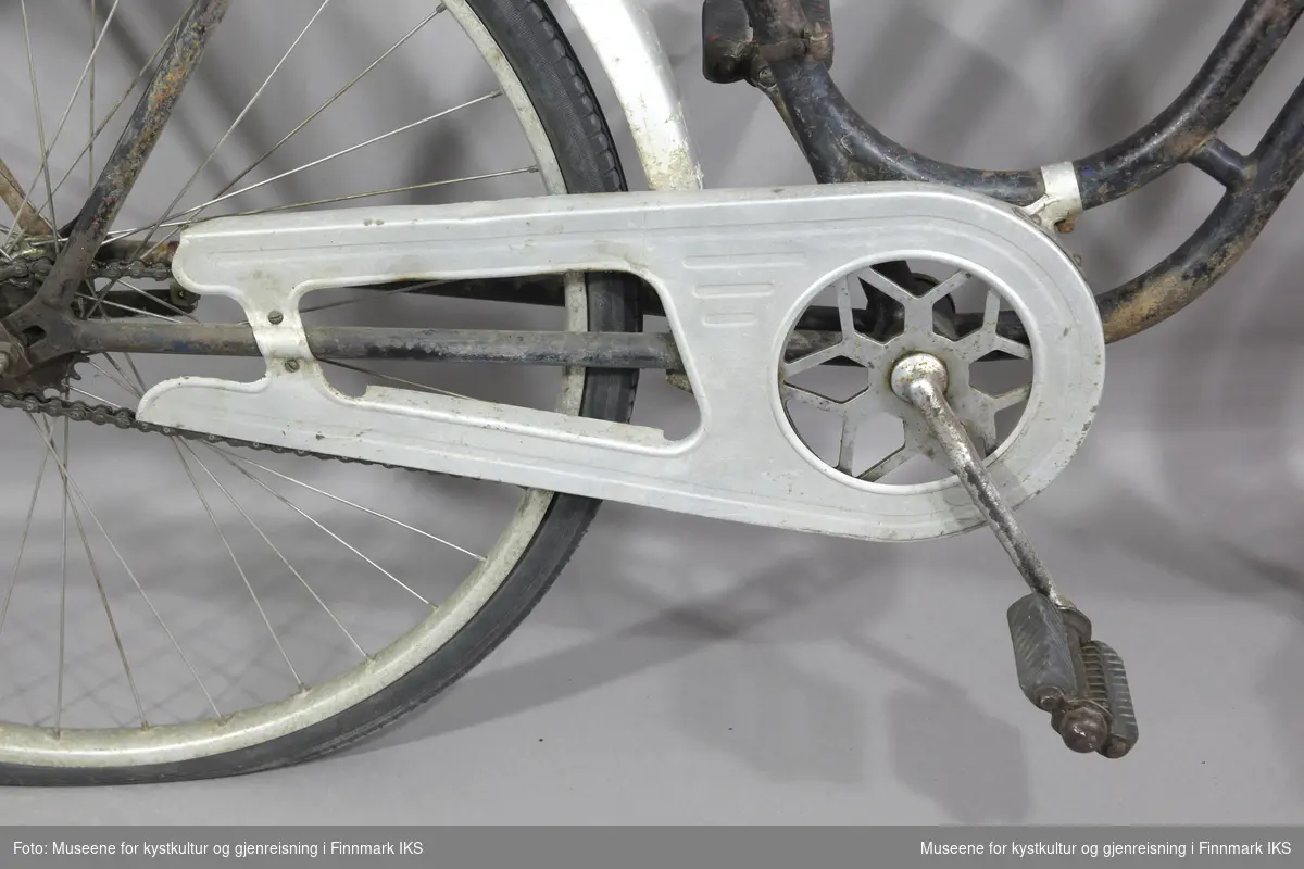 Sykkelen er sort og uten synlige varemerker. Den har en del rust, skjermene og kjedebeskytteren er metallfarget, sølvfarget. Håndtakene på styret er av hvit plast. På høyre side av styret er det ei håndbrems og på venstre side ei bjelle. Framme på ramma er det festet ei lykt med en dynamo som drives av omdreininger av forhjulet. Skjermen bak  har en refleks. Sykkelen har et bagasjebrett. Setet er av lær.