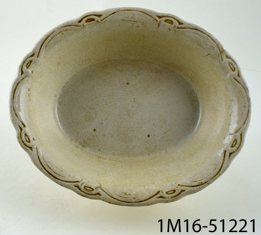 Oval karott i fajans eller flintgods med reliefdekor och vågig kant.
