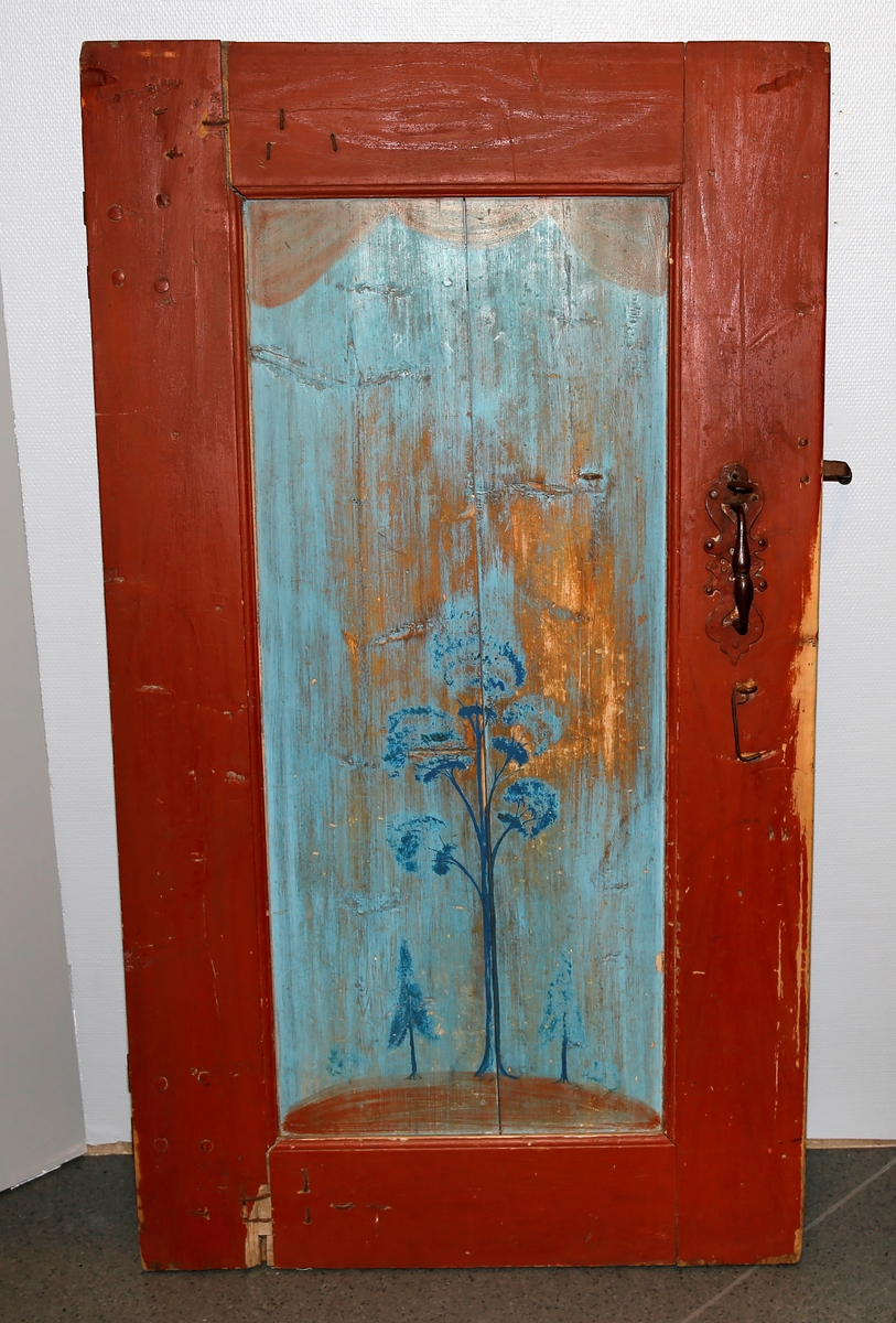 Rød omramming med ett avlangt dørspeil. Dørspeilet er lyseblått med blå trær.  Dørklinke med håndtak med fint utarbeidet jern. To dørhengsler.