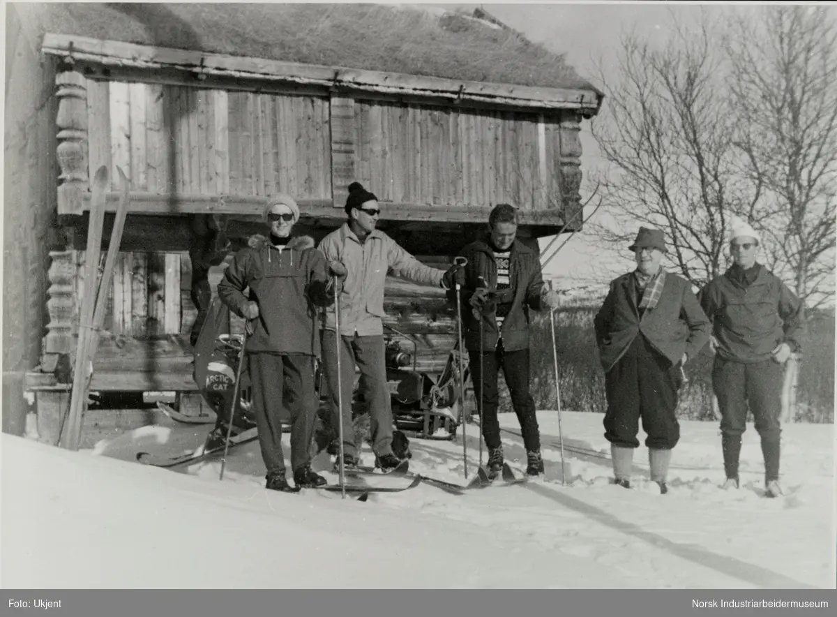Fire menn og en kvinne står i snøen foran Ellefstjønnburet på Sundet