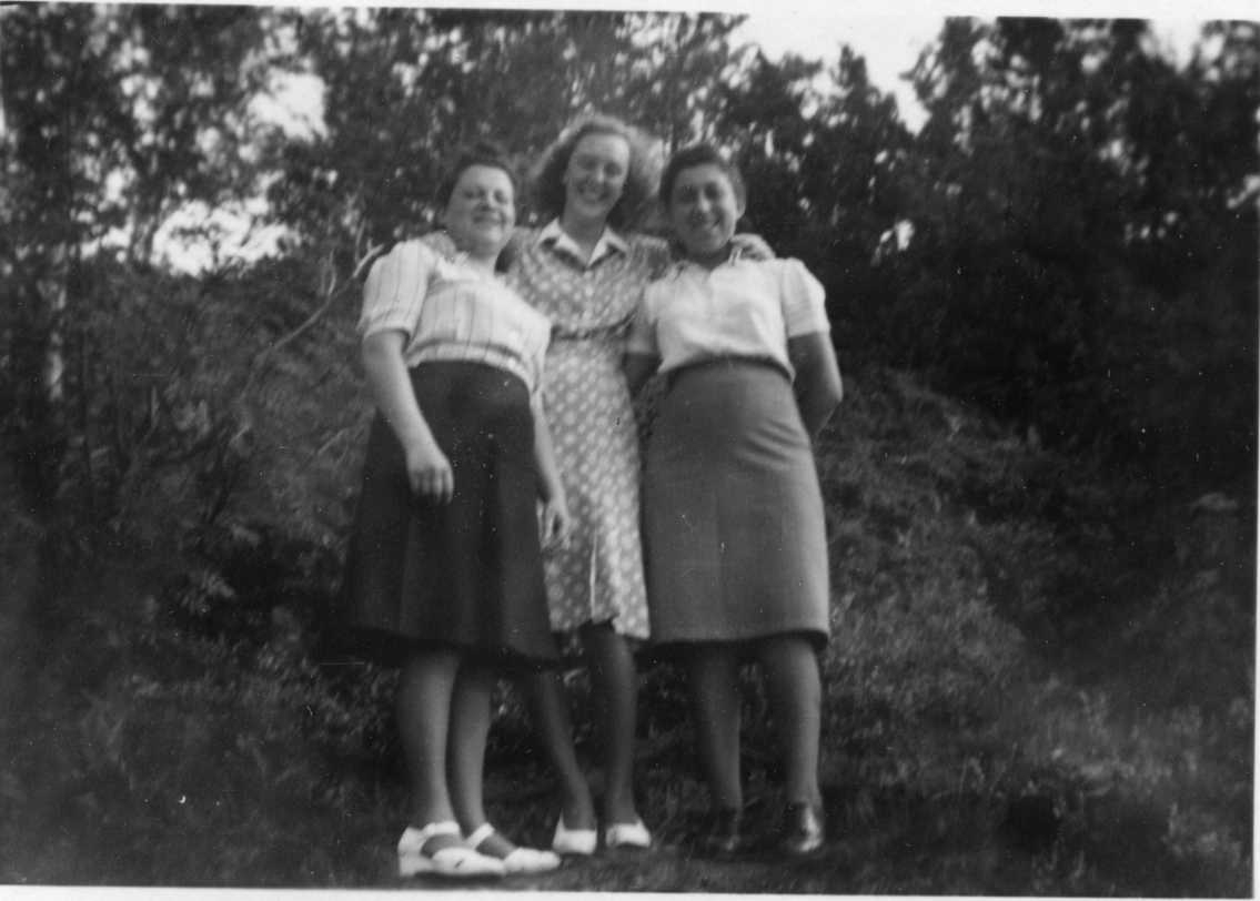 Tre unga kvinnor. Det är Inga-Lisa Johansson i mitten i prickig klänning som har armarna runt två polskor som står tätt intill. De bär ljus blus och kjol.