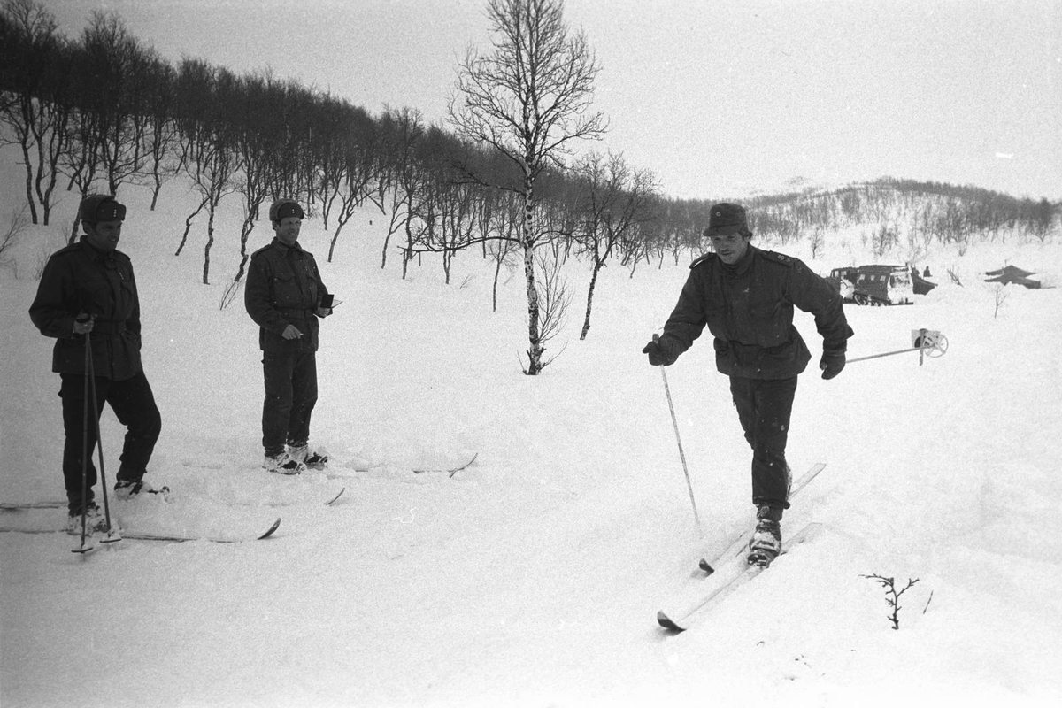Befalsskoleelev går på ski, to offiserer står til venstre.