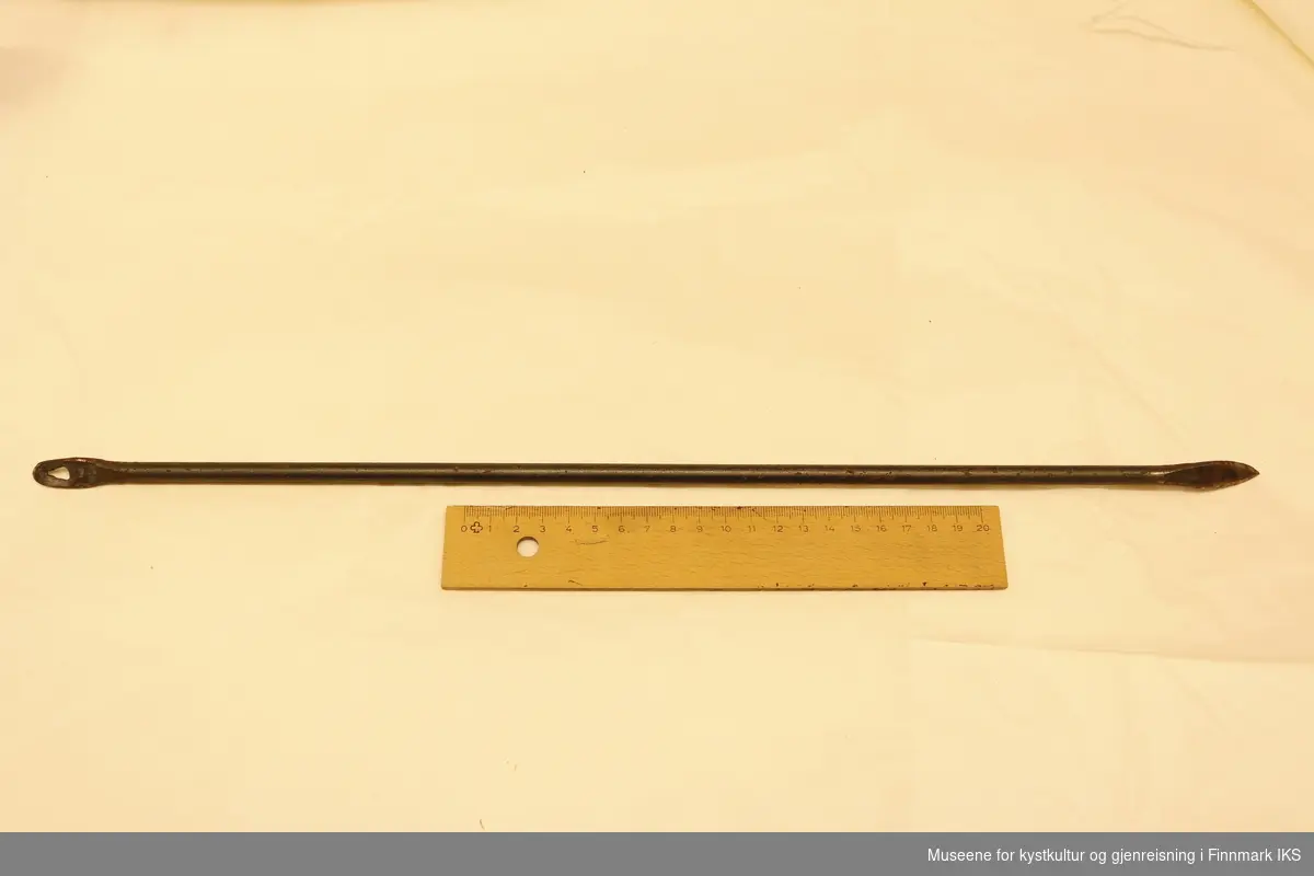 Halvmeter lang jernstang 1cm i diameter, med nåløye i ene enden og bøyd spiss i motsatt ende