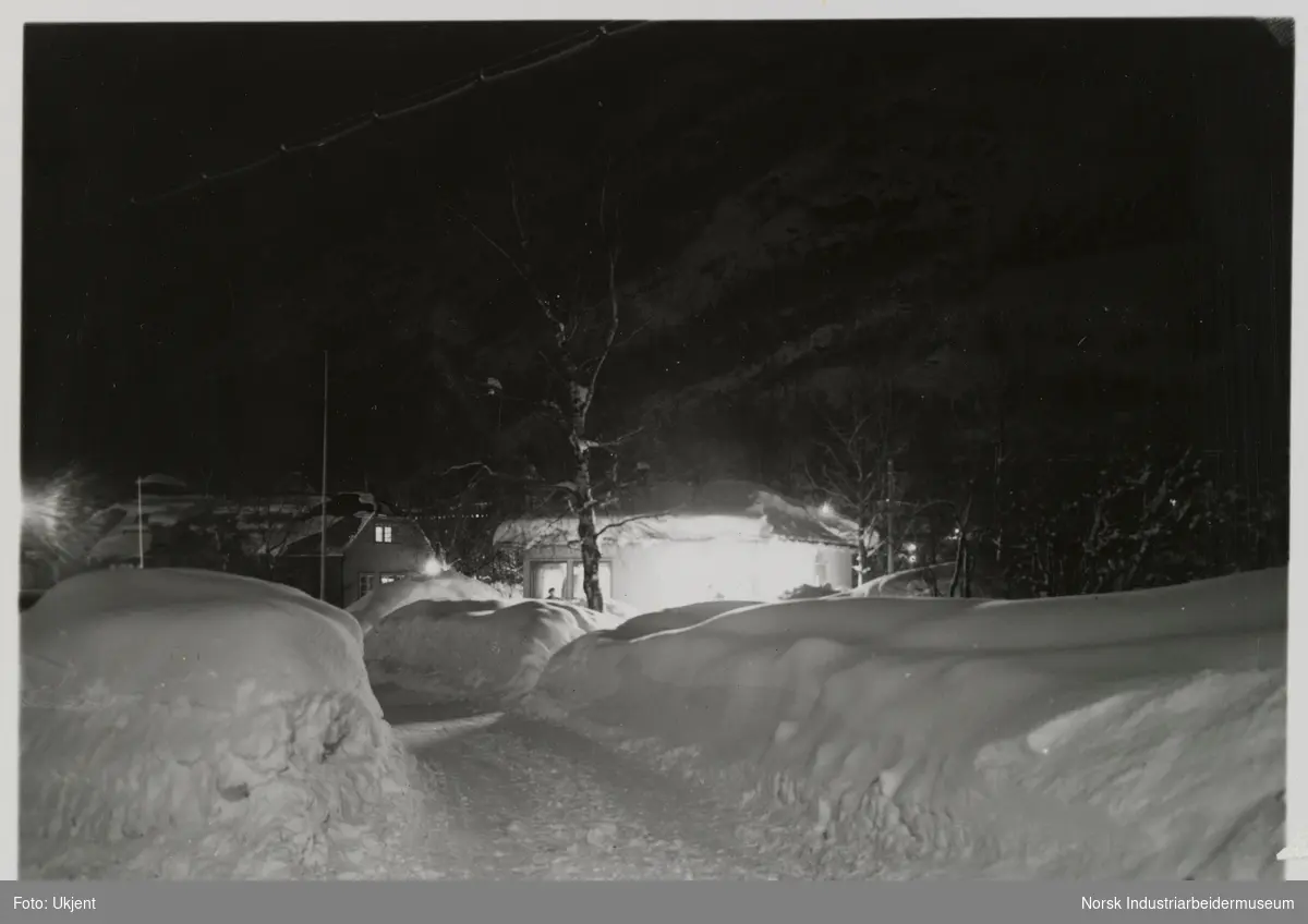 Opplyste hus i enden av en snødekt vei på Rjukan