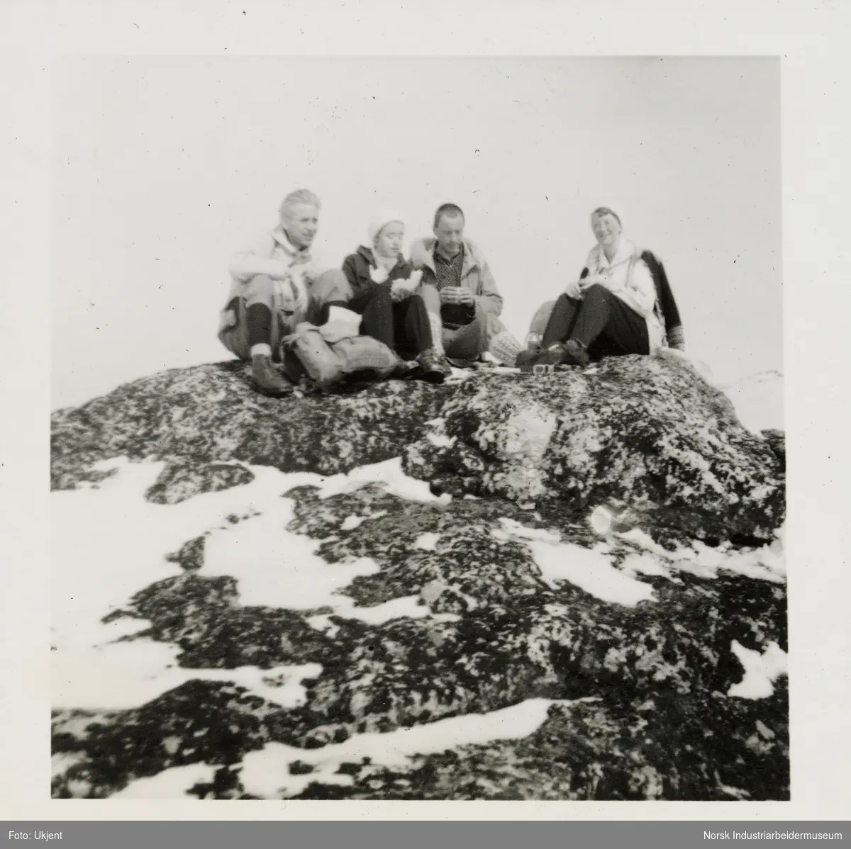 Fire mennesker tar seg pause på knaust på fjellet