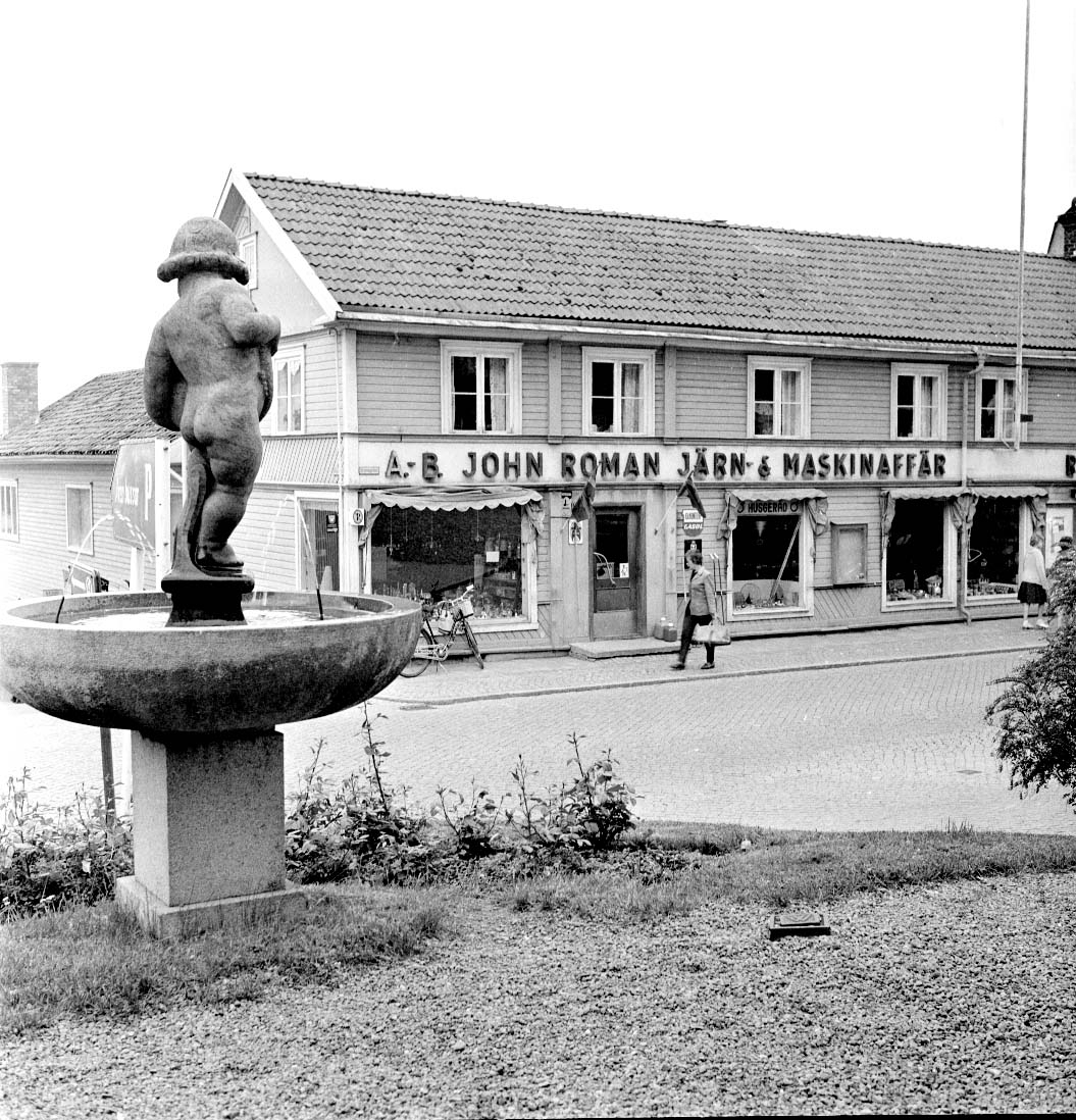Gränna torg från sydvästra hörnet med fontänen med skulpturen Botvid i förgrunden. På andra sidan Brahegatan syns kv Holländaren med "A-B John Roman Järn- & Maskinaffär".