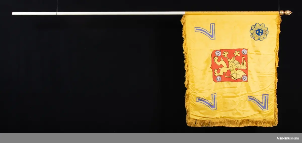 Dubbel gul duk, kantad med frans. Motiven fastsydda i applikation. Spetsen formad som en brinnande granat.
I mitten Östergötlands landskapsvapen. I hörnen siffran sju.
