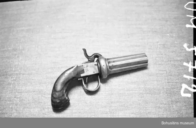 Ur handskrivna katalogen 1957-1958:
Fyrpipig revolver
L. 20 cm, av mässing m. kolv av trä; m. hane och av tryckare av järn; "J.ENGh"

Lappkatalog: 55