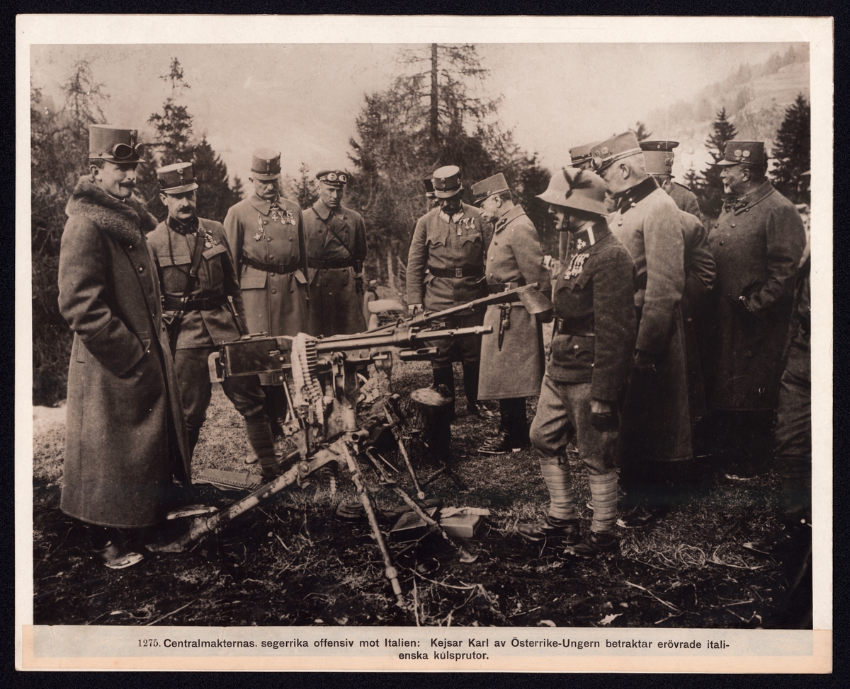 Bilden visar kejsaren av Österrike-Ungern Karl I på ett truppbesök. Han beskådar en kulspruta tillsammans med några soldater och officerare i en bergslandskap.