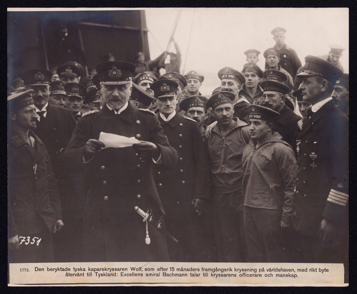 Bilden visar den tyska amiralen Gustav Bachmann som läser från ett papper framför en grupp sjömän från kryssaren SMS Wolf.