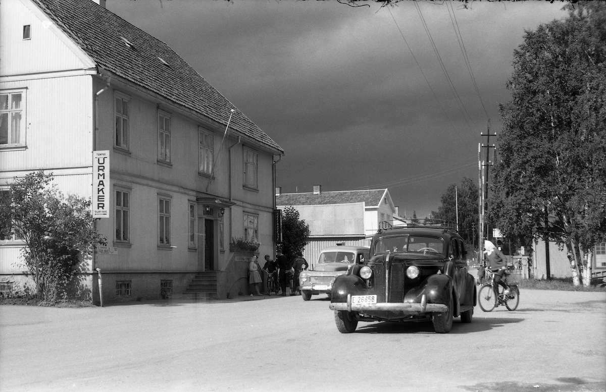 Gatebilde fra Lena september 1960. En tung og mørk himmel over Grand og videre oppover i Lenagata. Personene på bildet er ikke identifisert, men bilen i forkant er iflg. informant trolig en Buick 1937-modell..