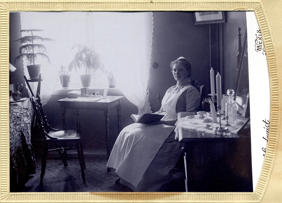 Foto av en ung sjuksköterska som sitter i sitt rum (trol. tjänstebostad på sjukhuset).