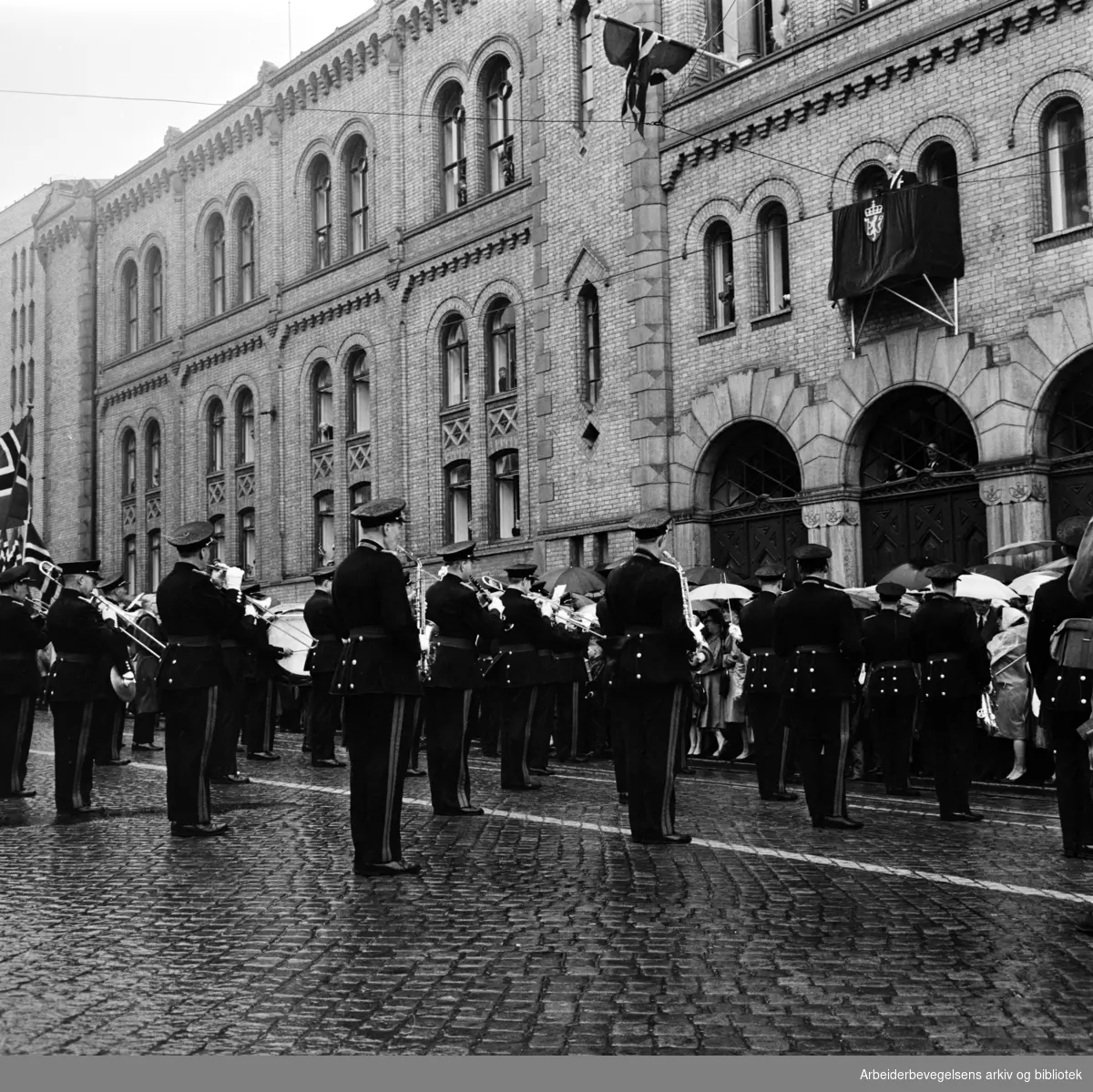 Divisjonsmusikken oppstilt utenfor Stortinget. Stortingspresident Nils Langhelle på balkongen. 17. mai 1962.