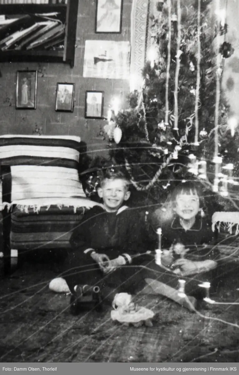 Honningsvåg. Stueinteriør med juletre. Gutten er Thor Damm Olsen, og jenta antas å være hans søster Eva. Slutten av 1930-tallet.