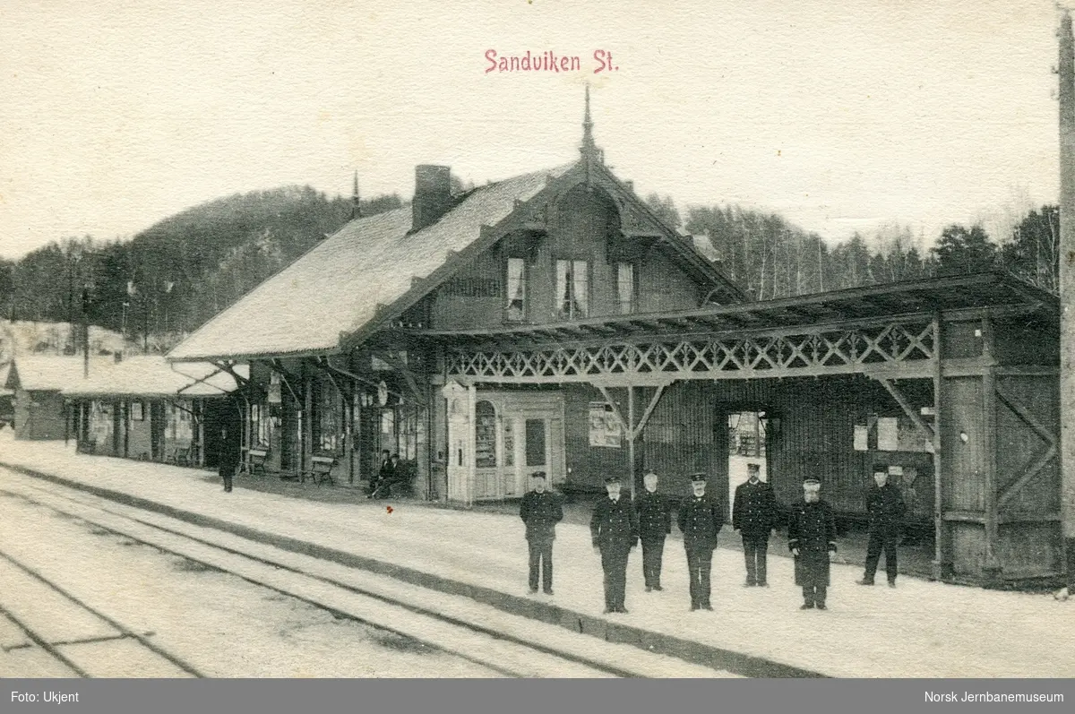 Sandvika stasjon. Stasjonspersonale og trolig stasjonsmesteren på plattformen.