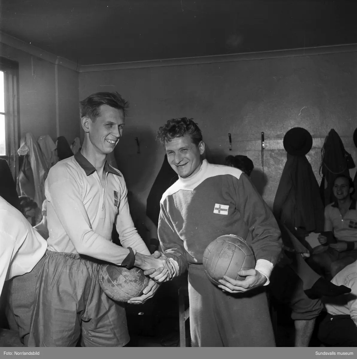Fotbollslandskamp Sverige-Finland 1952. Två spelare (lagkaptenerna?) skakar hand i omklädningsrummet.