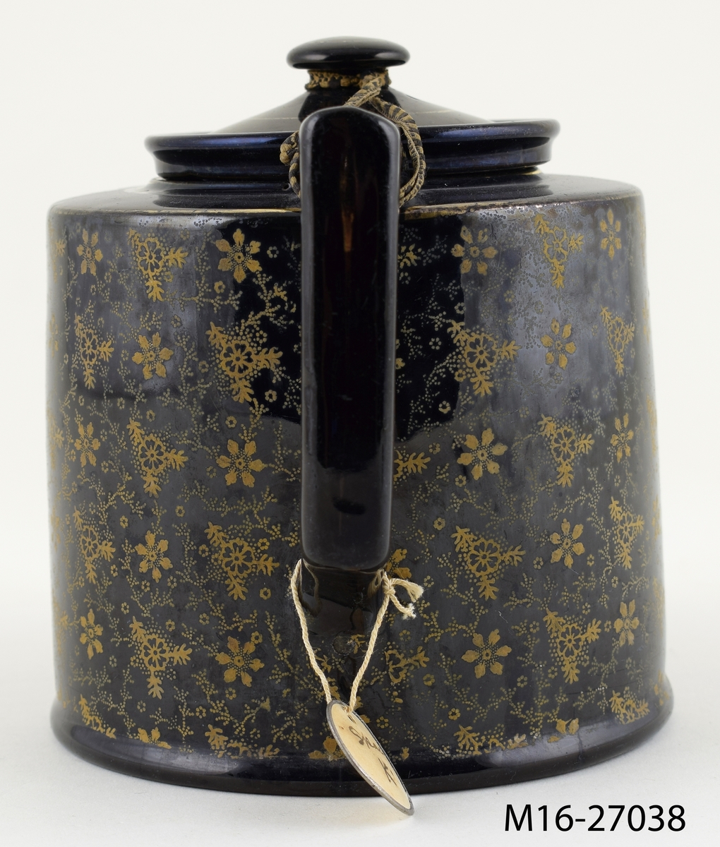 Tekanna, svart med tryckt småmönstrad dekor i brons/guld på de vertikala sidorna.
