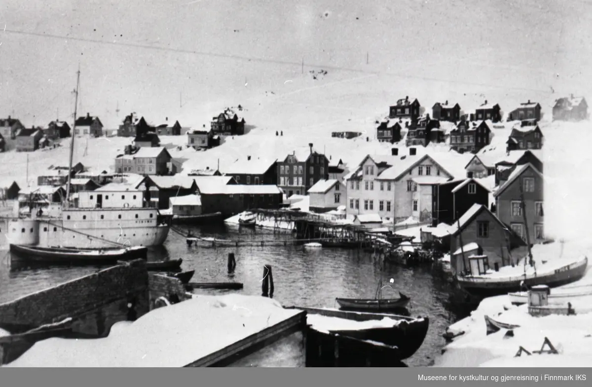 Honningsvåg. Vinterbilde. Havna med bebyggelse. T.v. hospitalskipet 'Viking' og t.h. den store hvite bygningen er Toklegården. 1920-årene.