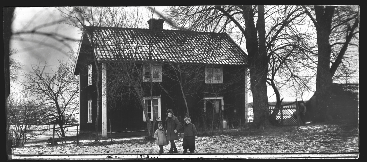 Tre barn framför hus