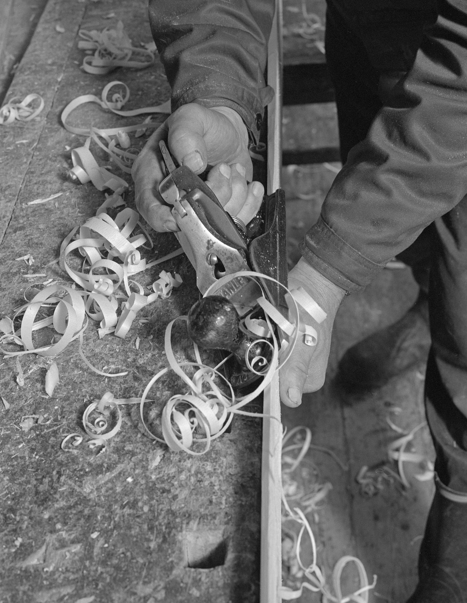 Bygging av fløterbåt («Flisa-båt») i Glomma fellesfløtingsforenings verksted på Breidablikk i Åsnes (Solør) i november 1984. Her står båtbygger Lars Bernhard Olastuen ved en lang høvelbenk og skrår kanten på et båtbord ved hjelp av en pusshøvel. Bordet var på forhånd grovbearbeidet med maskinhøvel.