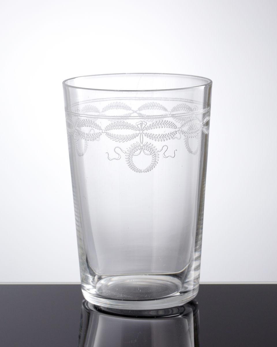 Dricksglas med pantograferad dekor i form av växtgirlanger och kransar i en bård på glasets övre del.
