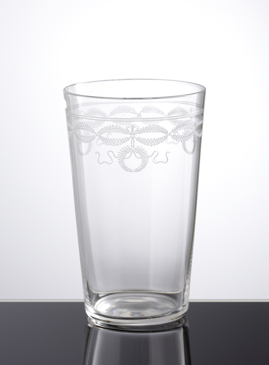 Dricksglas med pantograferad dekor i form av växtgirlanger och kransar i en bård på glasets övre del.