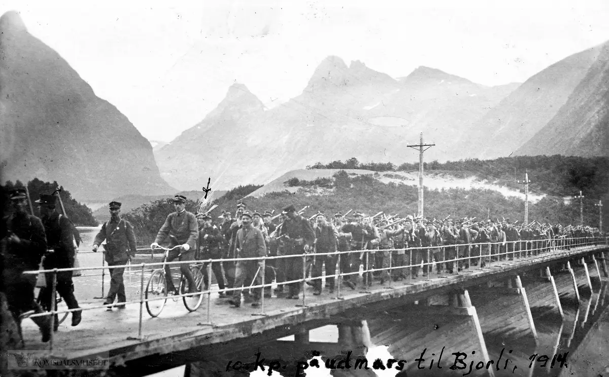 "10. kompani på utmarsj til Bjorli, 1914"...Bildet er tatt ved Grøttør bru, ved Rauma, ca. 2 kilometer fra Åndalsnes. I bakgrunnes ses Isterdalen og Trollstigen.