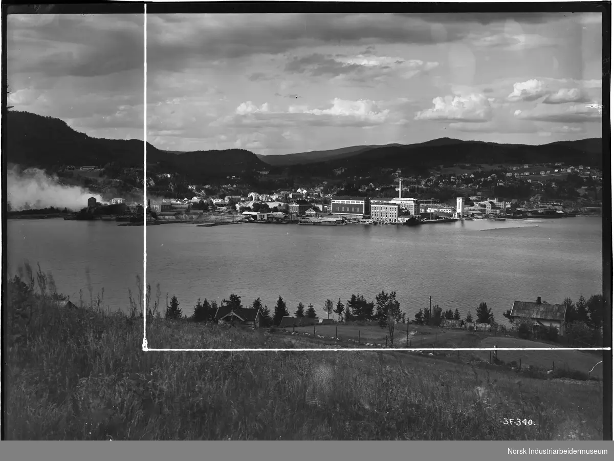 Notodden sett fra vestsiden av Heddalsvannet. Bryggen, industriområdet og boliger. Påtegnet strek i bildet, antagelig fotografens utvalg for produksjon av papirbilde.