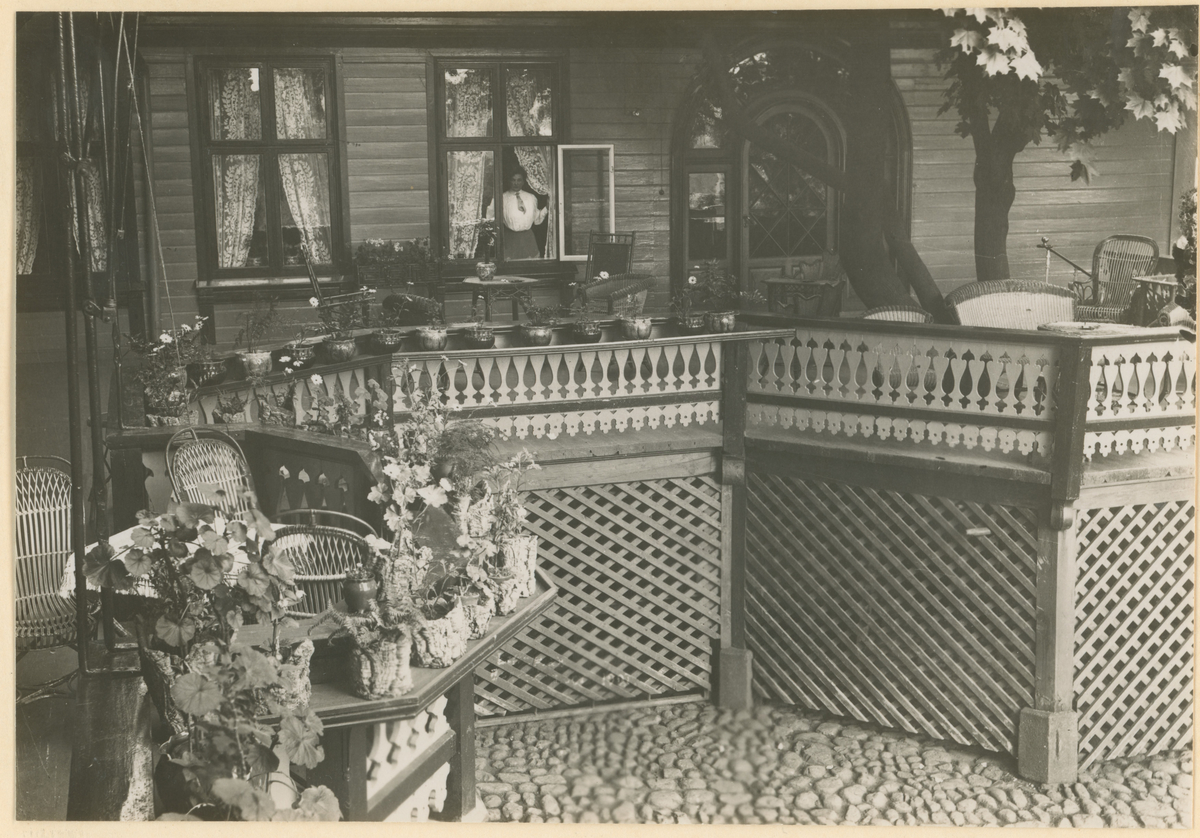 Fotograf har stått i gårdsplassen til Dronningens gate 3.
Detaljer: Deler av den berømte verandaen.
Historikk: Oppført av Louis Reinsch i 1858, solgt flere ganger. Fru Arnesen var eier 1883 - 1888, og senere datteren Margrethe Arnesen i perioden 1896 - 1911.