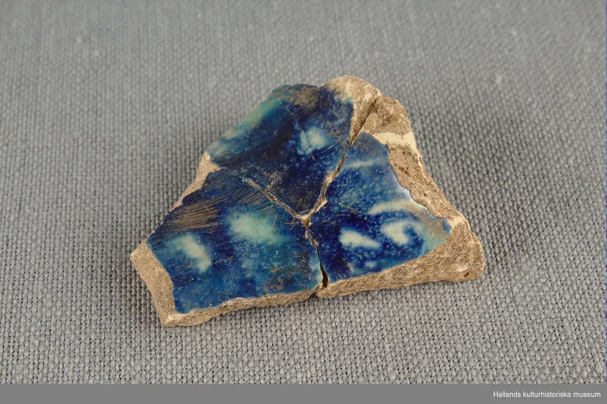 Skärva av drejat och glaserat lergods. Glaserat i blått och vitt. 

Ihoplimmad med föremålen vmf018735 och vmf018736.