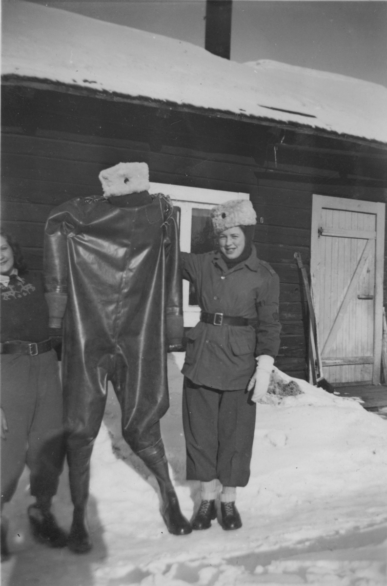 Två kvinnliga luftbevakare håller upp en våtdräkt, vintertid, 1942. Birgit Johansson till vänster och Karin Nordberg till höger. Luftbevakarna tillhörde 91:a ls-kompaniet i Tellejåkk, Kåbdalis under beredskapsåren.