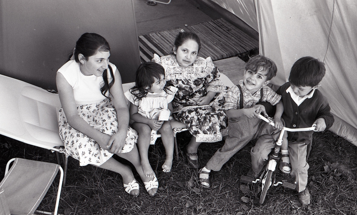 Några romska barn poserar framför kameran i Malmö sommaren år 1963. Bilden är tagen i samband med ett nyhetsreportage för Skånska Dagbladet. I reportaget porträtteras en romsk familj och hur de trivs med att ha blivit bofasta.