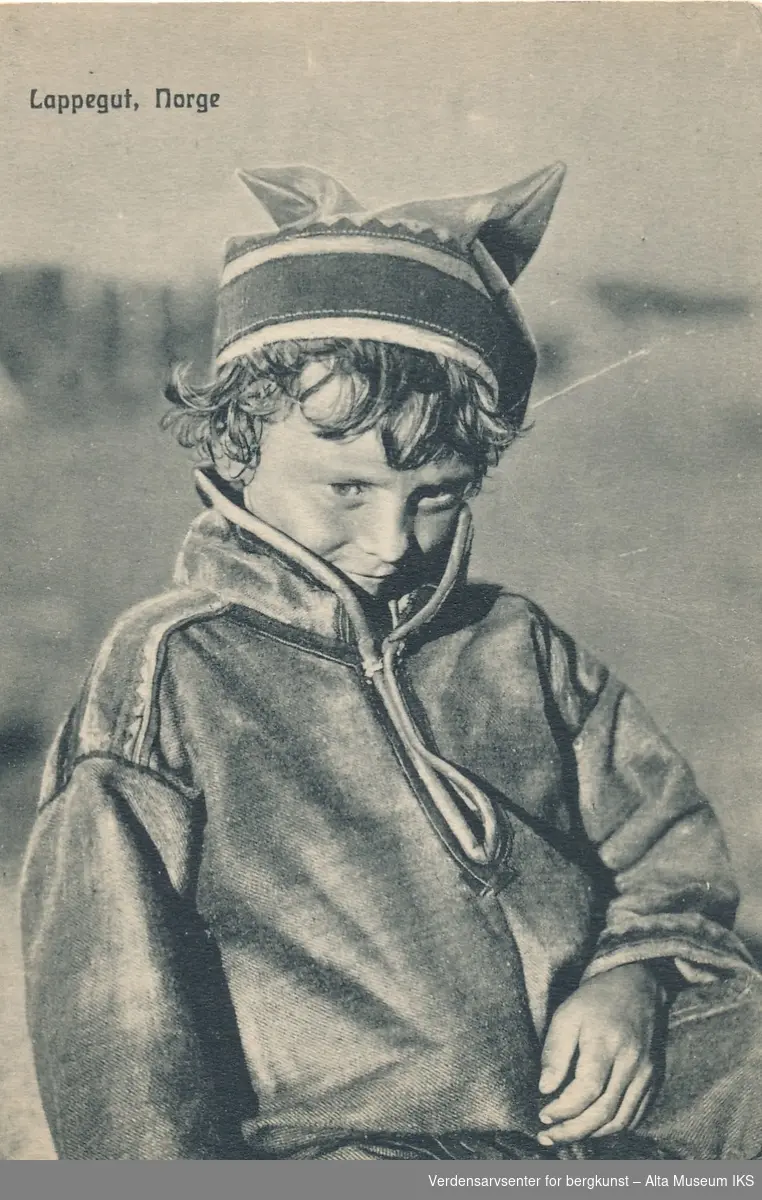Portrett av en samisk gutt. Han er ikledd kofte og lue.