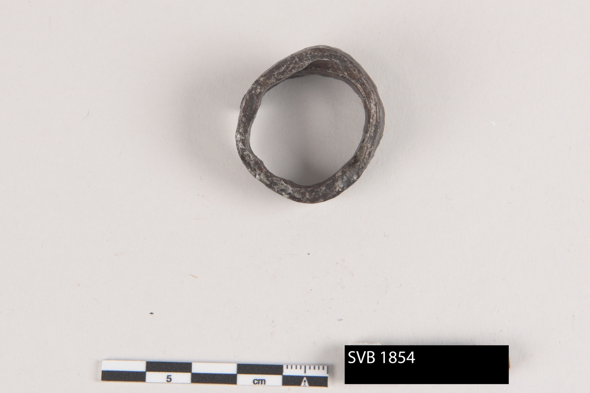 Ring av jern, laget av en flatbanket metallpinne. Ringen er ikke lukket. Den ble formet som en spiral og de endene er spisset.
