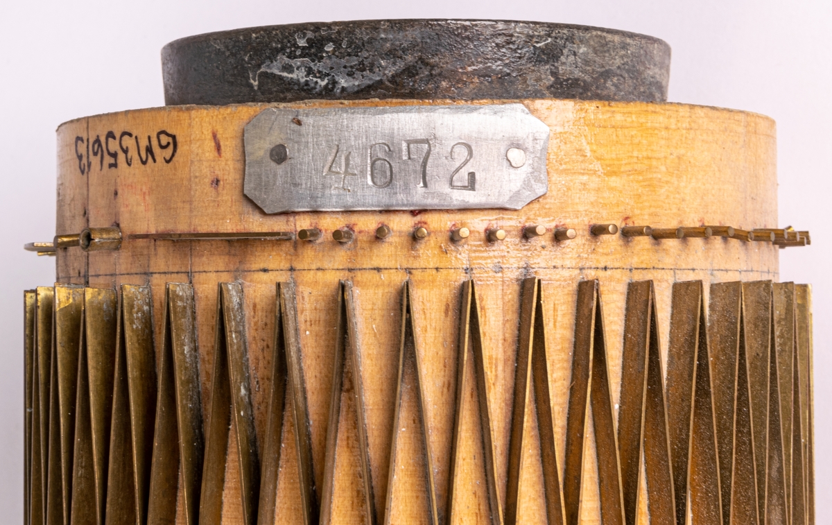 Tryckvals som använts vid tryckning av tapet vid Duro Tapetfabrik. Stomme av trä klädd med mönsterstift av metall. På valsen sitter en metallbricka med siffrorna 4672.