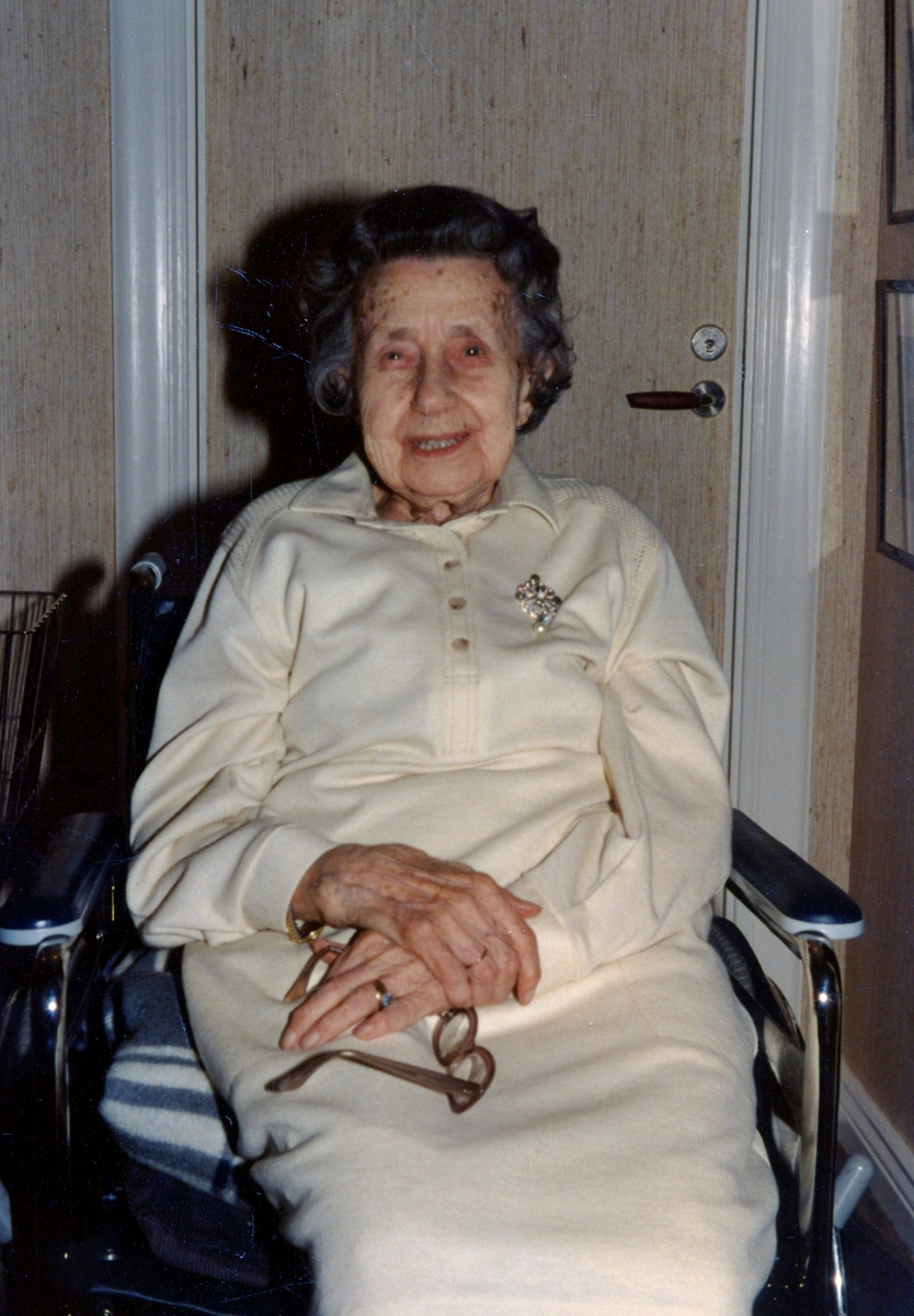 Margareta "Greta" Hernqvist (född 1895 i Göteborg, avliden 1984 i Kållered) sittandes i rullstol i Kålleredskolan i Livered cirka 1980. Hon arbetade som lärarinna 1914 - 1957. Relaterat motiv: A1533.